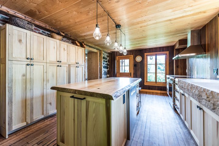 Armoires en bois clair et îlot, cuisine au plafond de bois